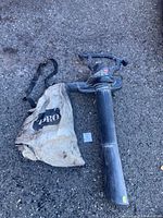 Full view of Toro blower vacuum with tube and collection bag on ground