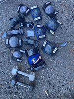 Overall view of Rollerblade pads and two dumbbells on ground