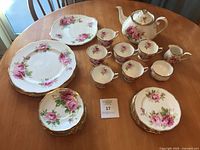 Full dinnerware set on table including teapot, sugar bowl, creamer, teacups, saucers, plates, platter
