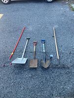 Five garden tools lined up on pavement