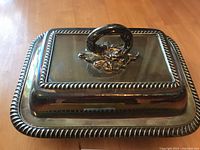 Lidded silver-plated serving dish, top view showing ornate handle and rope border