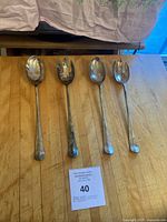 four silverplate serving utensils laid out on table
