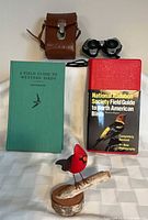 All items group shot: binoculars in case, two bird guides, red bird figurine