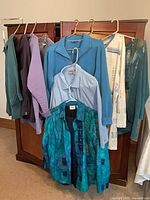 Seven tops hanging on armoire showing colors and styles