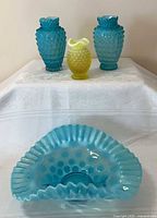 Group shot of two turquoise vases, one yellow vase, turquoise ruffled bowl