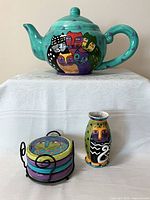 Overall view of teapot, vase, stacked coasters in holder