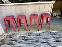 Four red metal bar stools lined at counter