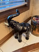 Full view of leather-wrapped elephant sculpture beside window