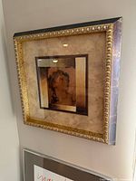 Oblique view of framed print showing image, mat, ornate frame
