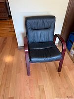 Front angled view of armchair showing leather upholstery and wood frame