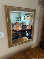 Front view of gold-tone framed mirror reflecting dining room