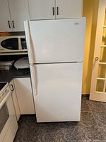 Front view of white Maytag top-mount refrigerator with surrounding cabinetry