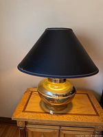 Front view of one brass table lamp with black shade