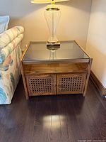 Front view of one side table showing glass top, cane doors