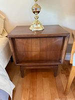 Front view of first nightstand showing walnut finish, framed recessed drawer fronts, tapered legs