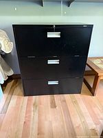 Front view of black three-drawer filing cabinet showing overall condition