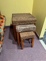 Three stacked woven nesting tables, showing tops and legs