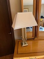Full view of lamp on dresser showing brass base, dual columns, shade