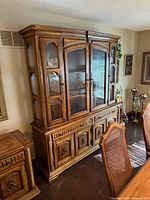 Front view of entire two-piece china cabinet showing upper glass hutch and lower carved base