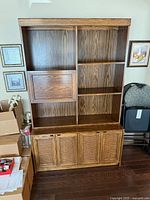 Full view of wall unit showing upper shelves, drop-front door, lower cane-panel doors