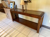 Front angled view of wood console table showing glass-covered cane top and lower shelf
