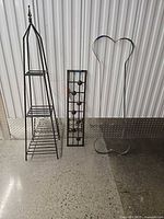 Full view of all three metal items: obelisk, coat rack panel, trellis