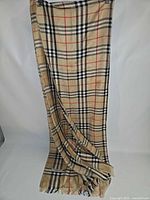 Full view of Burberry London rectangular camel check scarf hanging, showing overall size and fringe