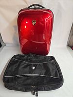 Front view of metallic red Heys hardside carry-on suitcase and separate black mesh divider panel