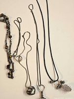 All five necklaces laid out showing pendants and chain styles
