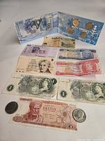 Overall view of all banknotes laid out with Sochi coin folder open at top and two Kennedy half dollars visible