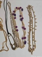 All five gold-tone Monet long necklaces laid flat showing styles
