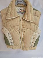 Front view of White Stag Mountain Goat beige/olive puffer vest on hanger