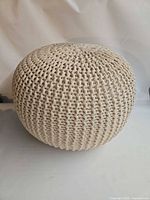 Full view of cream knitted round pouf ottoman