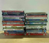 Two stacks totalling roughly 28 Christmas DVDs showing spines for identification