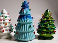 Front view of three ceramic Christmas trees showing colors and bulb accents
