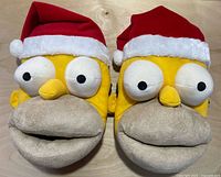 Top view of the two Homer Simpson slippers showing plush faces and Santa hats