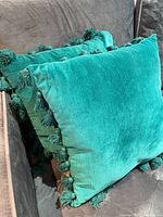 Two teal tassel pillows on couch