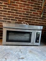 Front view of microwave showing stainless exterior, control panel, missing handle