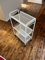 Full view of white IKEA HORNAVAN rolling cart showing three mesh shelves and casters