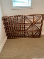 Front view of full wooden wine rack showing lattice bottle holders and cross-brace section