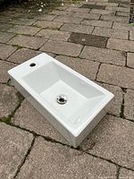 Top and side view of rectangular white ceramic sink showing faucet hole and drain