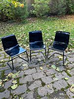 Front view of three black acrylic IKEA Tobias chairs on patio