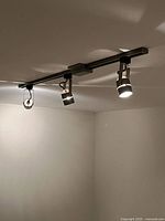 Three-light section of track lighting mounted to ceiling