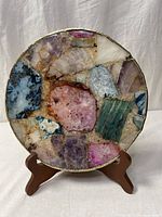 Front view of circular plate showing multicoloured stone mosaic and gold trim