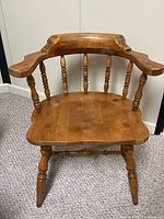 Front view of solid wood captain’s chair showing curved backrest, spindle supports, contoured seat, turned legs