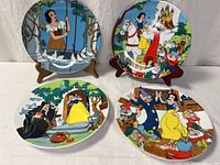 All four Snow White collector plates displayed on table