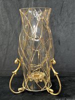 Full view of hurricane candle holder showing glass body, metal vine overlay and scroll base