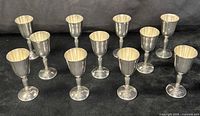 All 12 Pilgrim silverplate goblets grouped on black backdrop