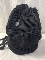 Full view of black crochet The Sak backpack showing front pocket and drawstring top