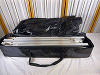 Black carry bag opened showing aluminum frame pieces